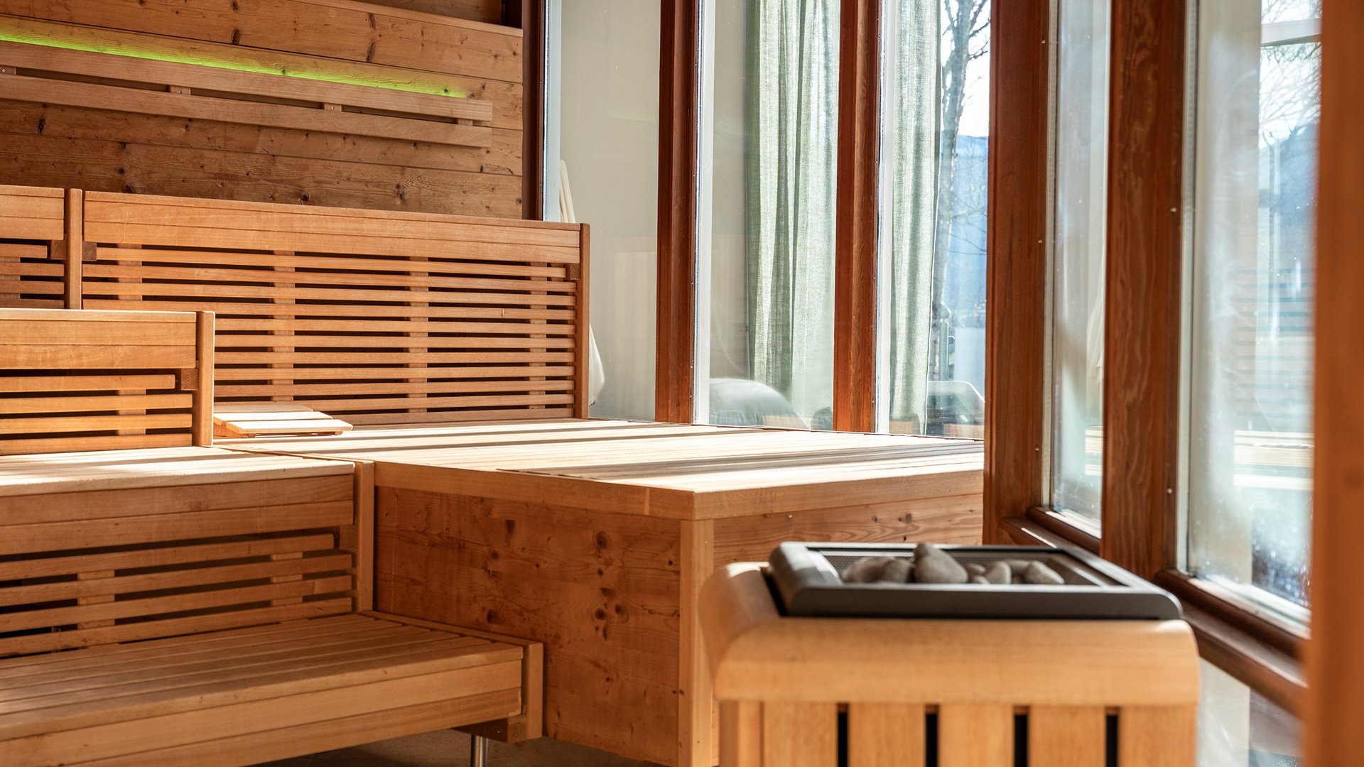 Helle Saunalandschaft mit Holzbänken und großen Fenstern mit Ausblick