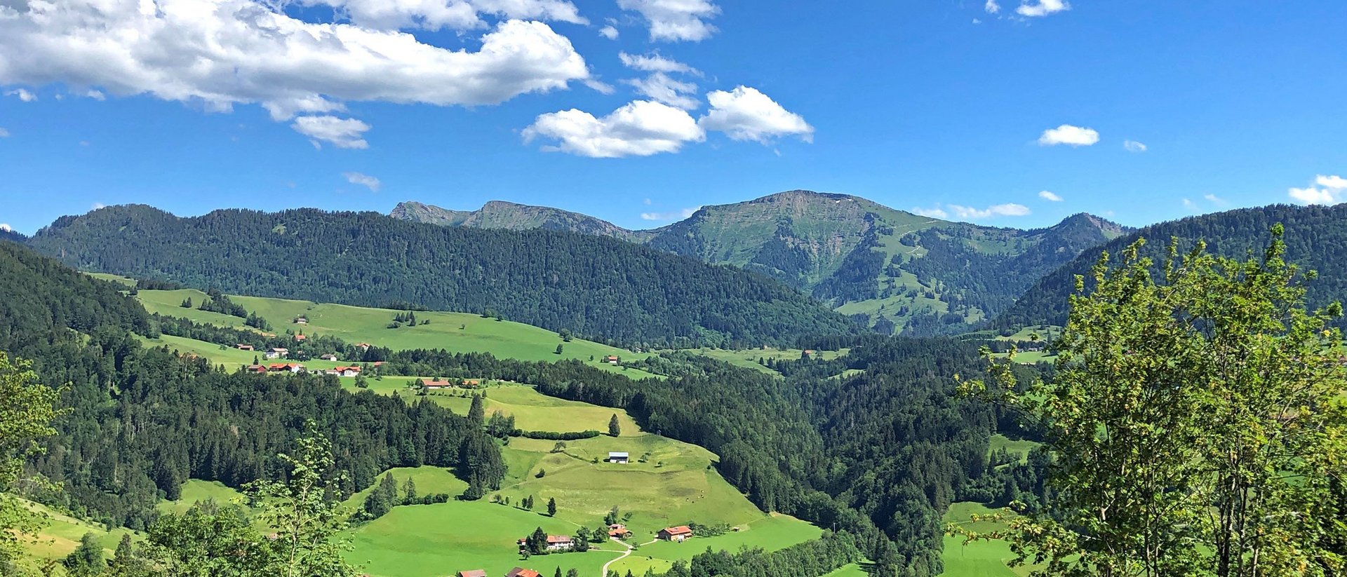Wissen, das inspiriert: Unsere Vortragsreihe greift Themen auf, die das Leben bereichern. Grüne Hügel und Berge unter blauem Himmel mit einigen Wolken