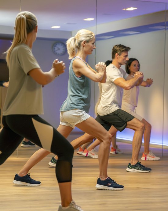 Fitness group doing stretching and balance exercises in studio in front of mirror