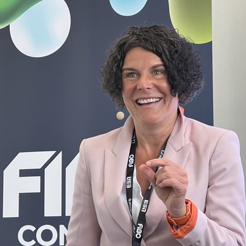 Wissen, das inspiriert: Unsere Vortragsreihe greift Themen auf, die das Leben bereichern. Frau in rosa Blazer spricht vor FIBO-Logo und macht Handgeste