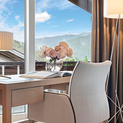 Karriere: Arbeiten im Hotel im Allgäu Schreibtisch mit Stuhl vor Fenster mit Bergblick und Vase mit Blumen