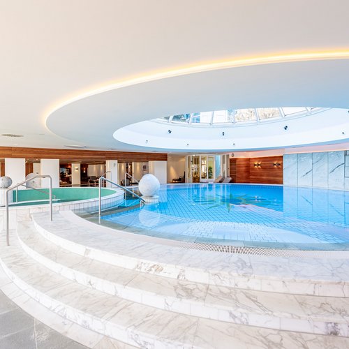 Das Breathwork Retreat Hallenbad mit rundem Oberlicht und Marmorstufen in modernem Spa