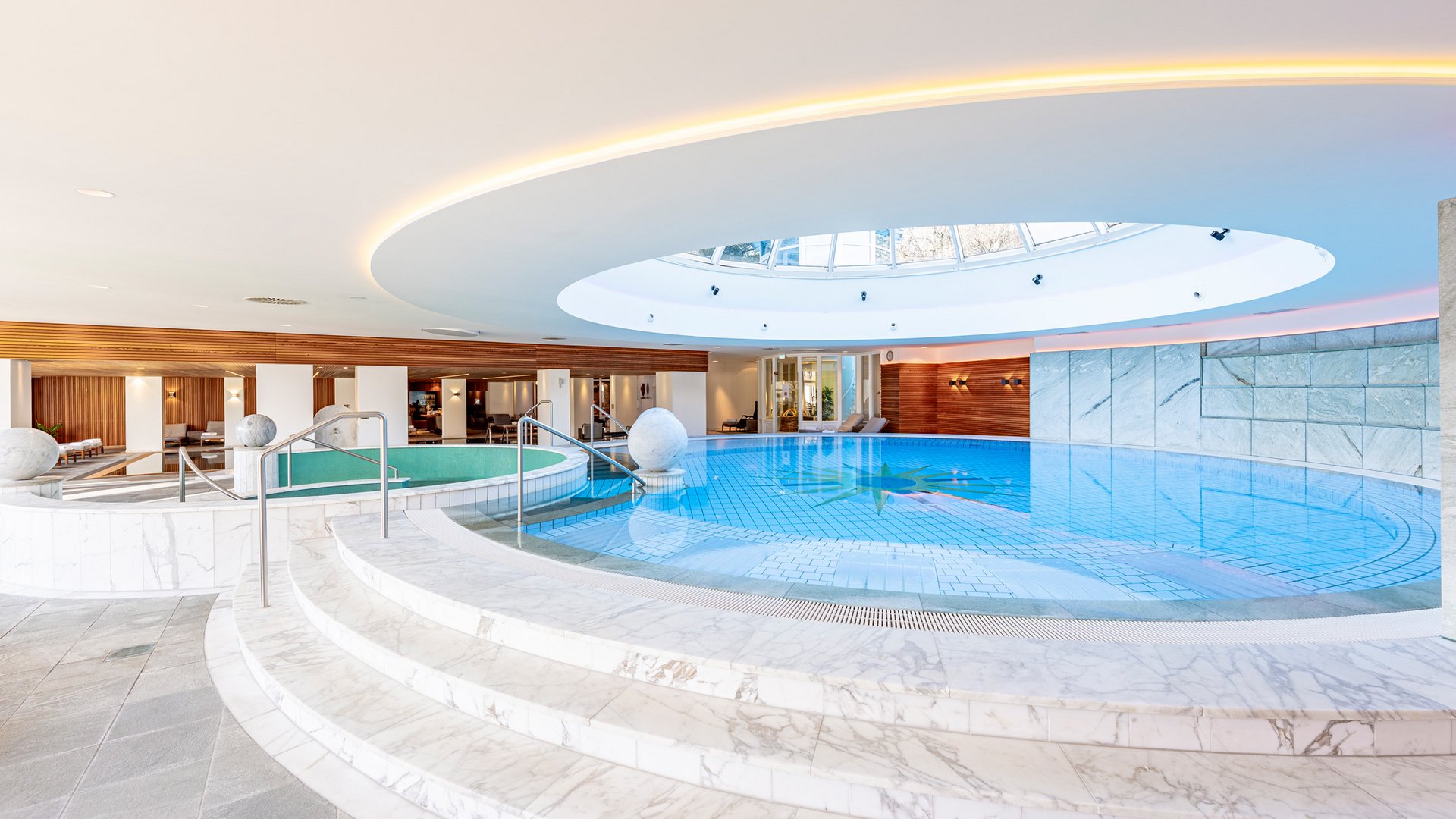 Hallenbad mit rundem Oberlicht und Marmorstufen in modernem Spa
