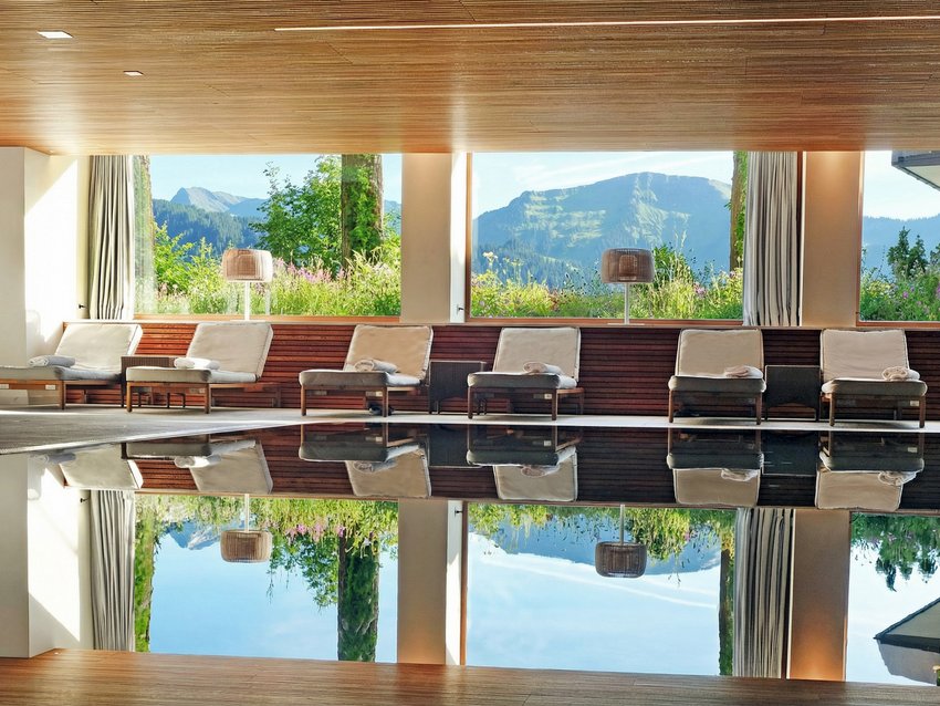 Indoor pool with lounge chairs and mountain view through large windows