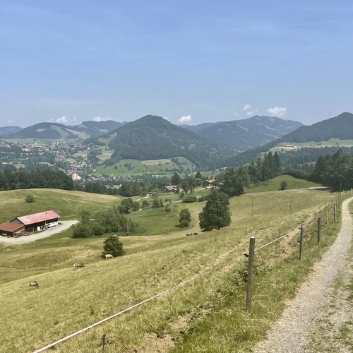 Radfahrer auf Bergweg mit Blick auf grüne Hügel und Dorf in der Ferne