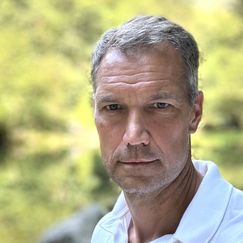 Nahaufnahme eines ernst blickenden Mannes vor unscharf grünem Hintergrund