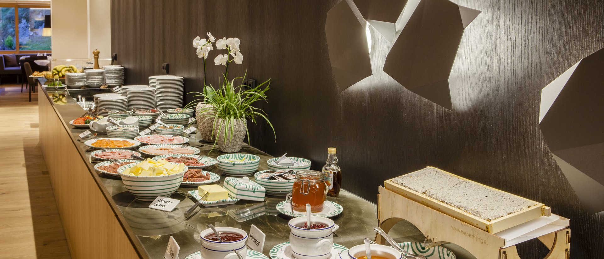 Buffet mit Aufstrichen, Käse, Honig und Geschirr in modernem Raum