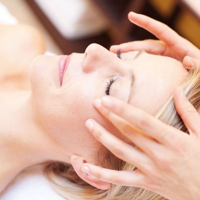 Frau erhält entspannende Gesichtsmassage mit geschlossenen Augen