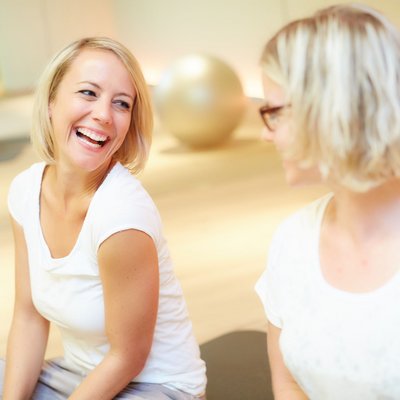 Unser Auftrag: Ihr perfekter Urlaub in Oberstaufen Zwei Frauen lachen zusammen in einem Fitnessraum mit Gymnastikbällen