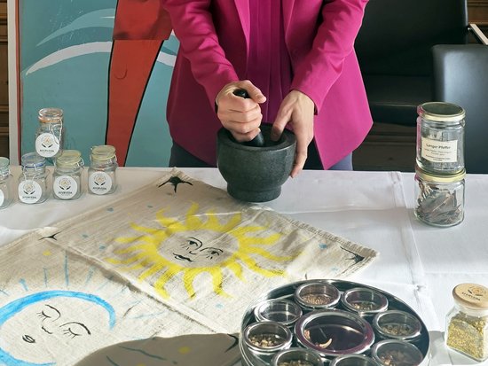 Person grinding spices in mortar with Ayurveda herbs on table