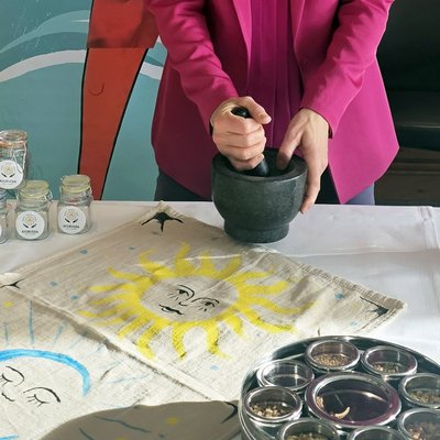 Wissen mit Weitblick – Vortragsreihe im Allgäu | Hotel Allgäu Sonne Person zerkleinert Gewürze in Mörser mit Ayurveda-Kräutern auf Tisch