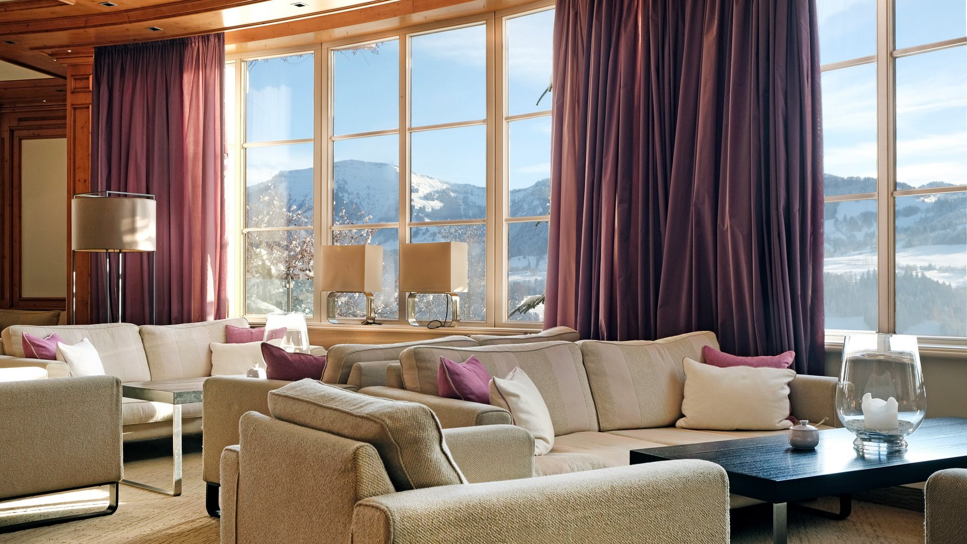 Gemütliches Wohnzimmer mit hellen Sofas und großen Fenstern mit Bergblick