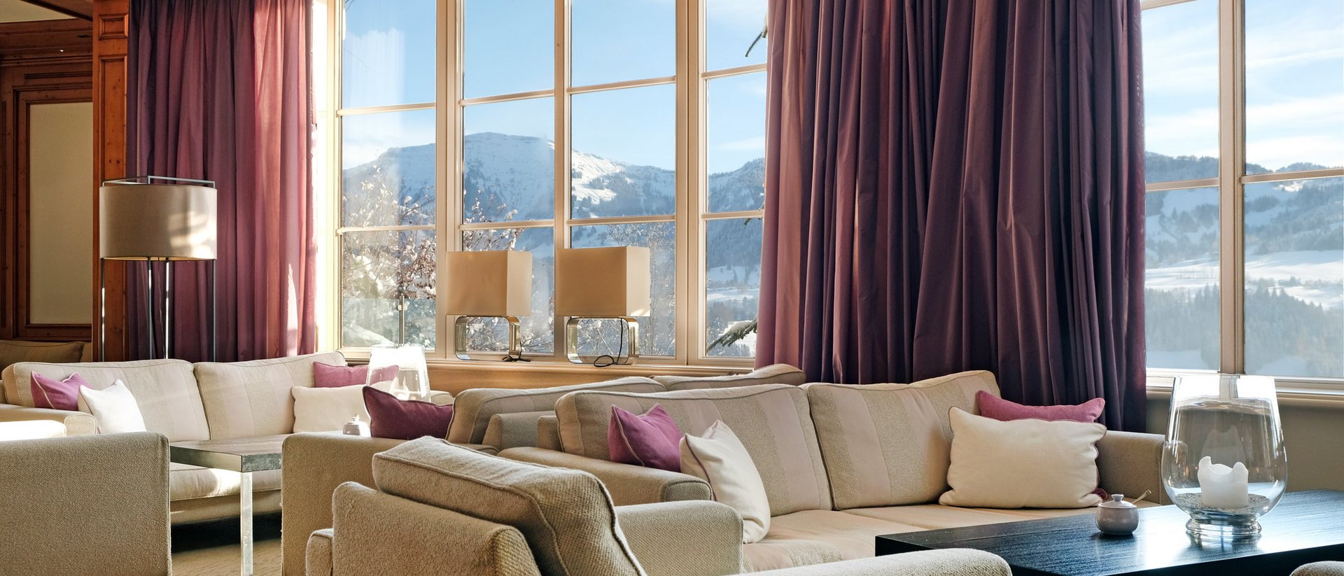 Gemütliches Wohnzimmer mit hellen Sofas und großen Fenstern mit Bergblick