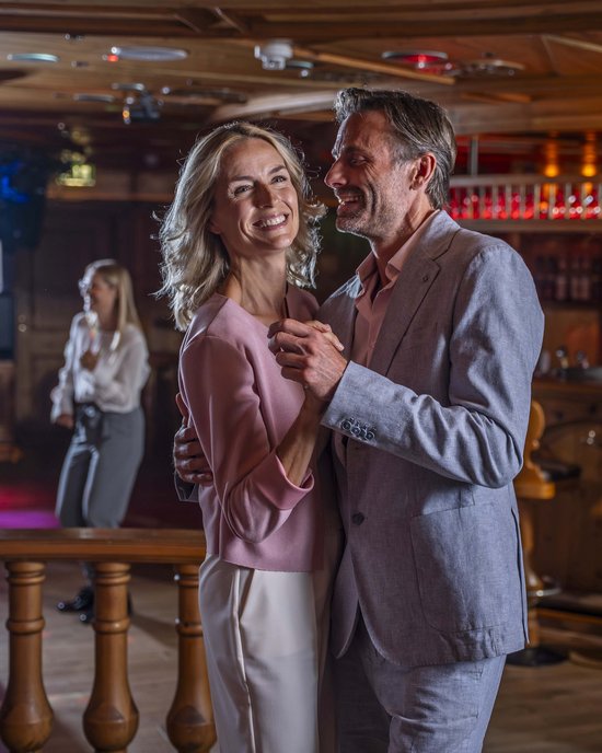 Couple happily dancing in rustic bar setting with other guests in background