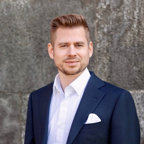 Wissen, das inspiriert: Unsere Vortragsreihe greift Themen auf, die das Leben bereichern. Porträt eines Mannes in Anzug vor grauer Betonwand