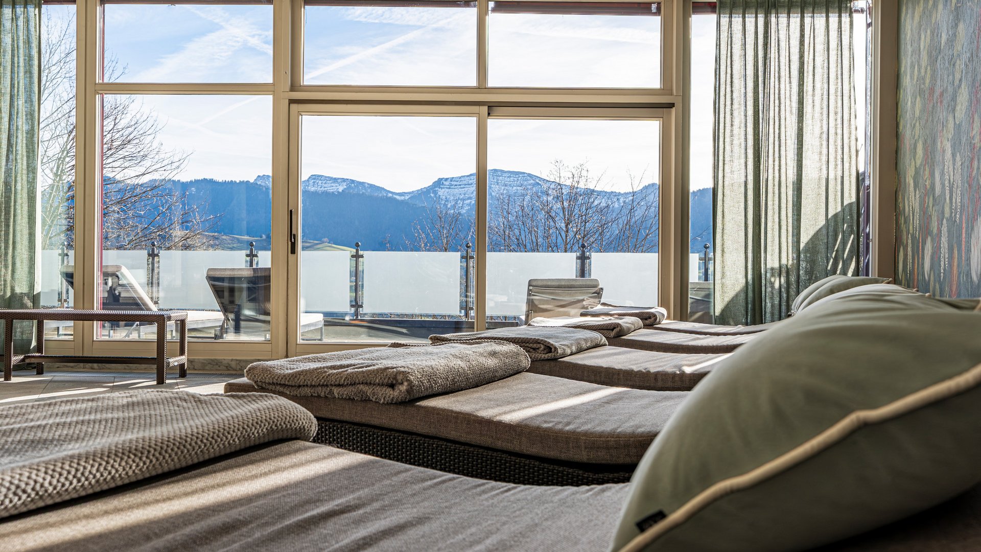 Entspannungsraum mit Liegestühlen und Blick auf verschneite Berge