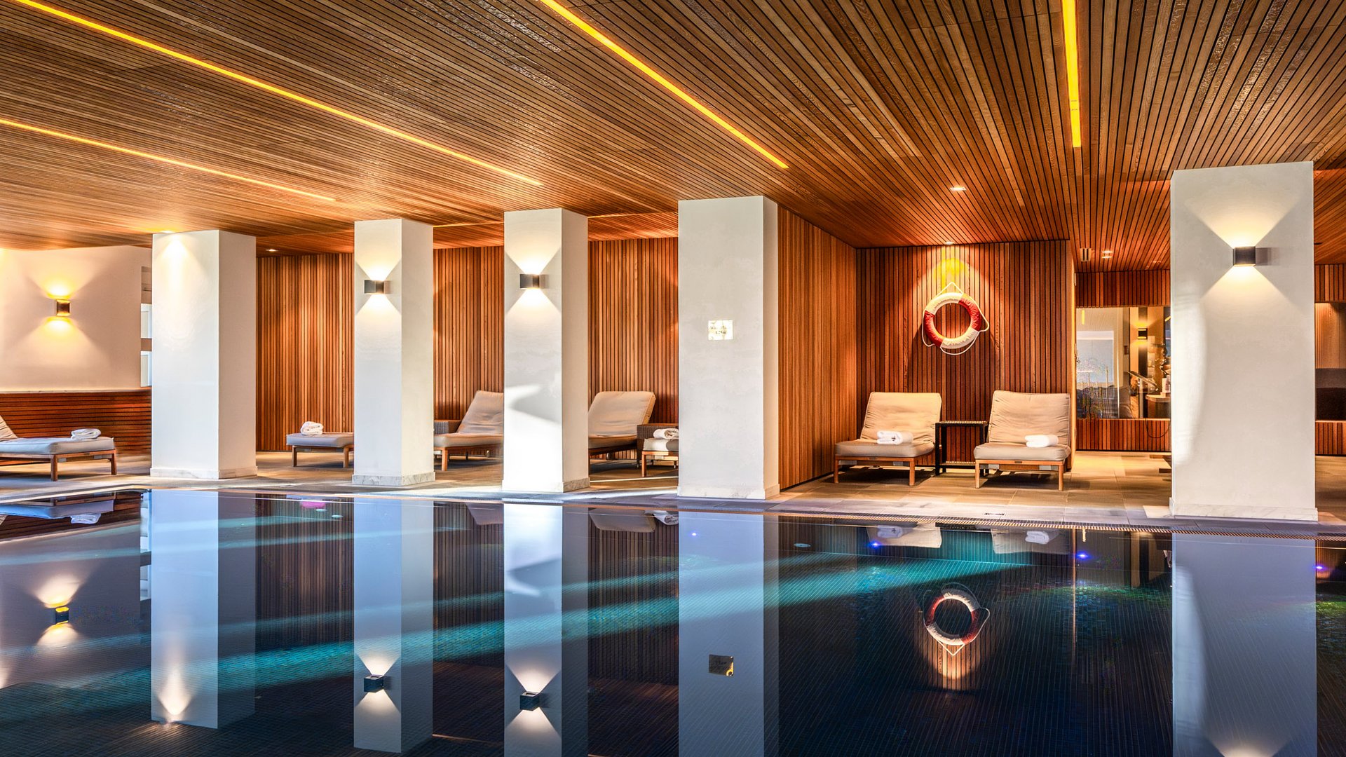 Beheizter Innenpool mit Holzdecke und Liegestühlen in einem stilvollen Wellnessbereich