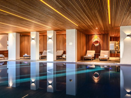 Your spa hotel in Allgäu: Allgäu Sonne Heated indoor pool with wooden ceiling and lounge chairs in a stylish spa area