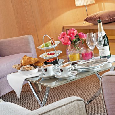 Breakfast with croissants, coffee, juice, champagne, and fruit on a glass table