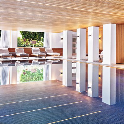 Innenansicht eines modernen Hallenbads mit Liegestühlen und großen Fenstern