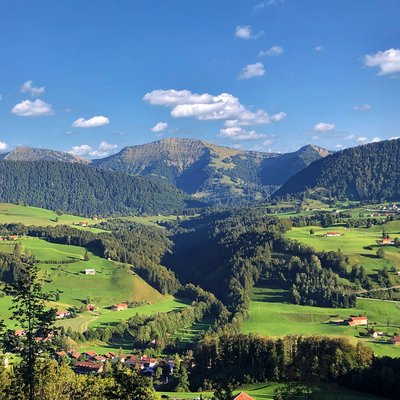 Green hills and mountains under blue sky with scattered clouds