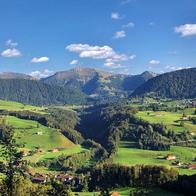 Green hills and mountains under blue sky with scattered clouds