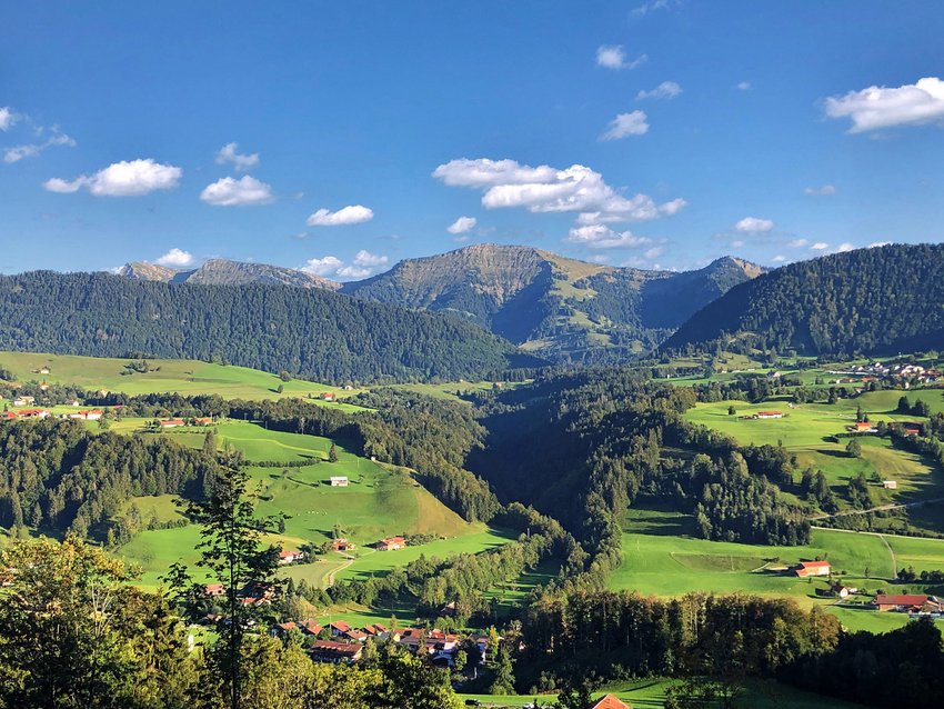 Grüne Hügel und Berge unter blauem Himmel mit vereinzelten Wolken