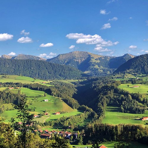 Grüne Hügel und Berge unter blauem Himmel mit vereinzelten Wolken