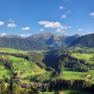 Grüne Hügel und Berge unter blauem Himmel mit vereinzelten Wolken