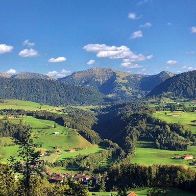 Grüne Hügel und Berge unter blauem Himmel mit vereinzelten Wolken