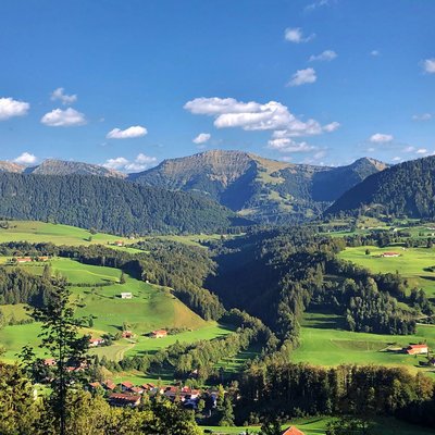 Green hills and mountains under blue sky with scattered clouds