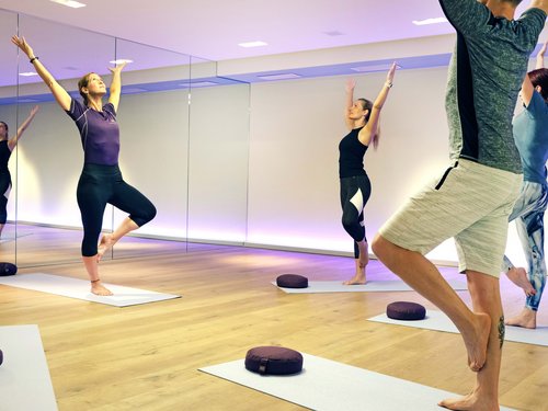Yoga-Kurs mit Frauen und Mann, die Baum-Pose in einem Studio ausführen