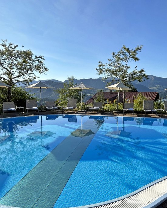 Leerer Pool mit Sonnenschirmen und Liegestühlen vor Berglandschaft