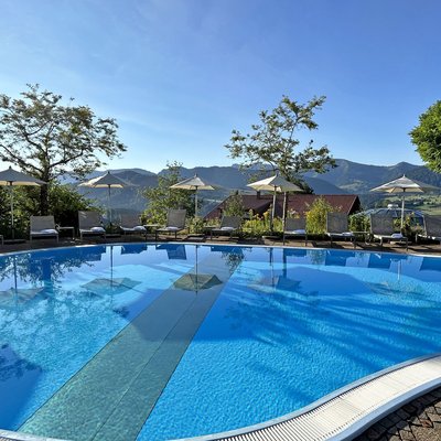 Leerer Pool mit Sonnenschirmen und Liegestühlen vor Berglandschaft