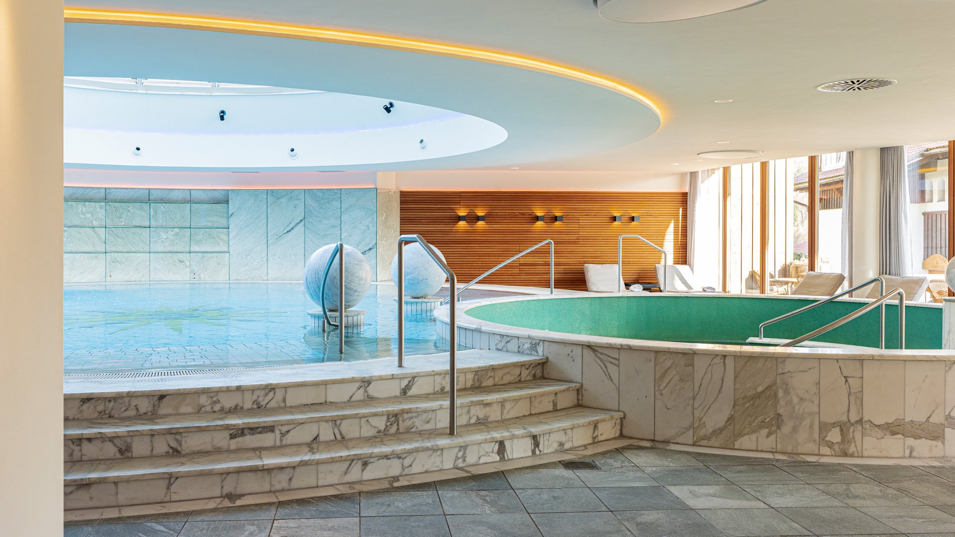 Innenansicht eines Wellnessbereichs mit runden Pools und Marmorverkleidung
