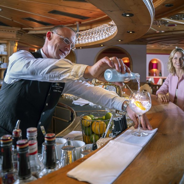 Barkeeper gießt Getränk für ein Paar an der Bar in gemütlicher Holzumgebung