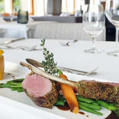 Hotel im Allgäu: 5-Sterne-Gesundheitsurlaub in Bayern Gourmet-Lammkoteletts mit Gemüse und gefüllter gelber Paprika auf weißem Teller