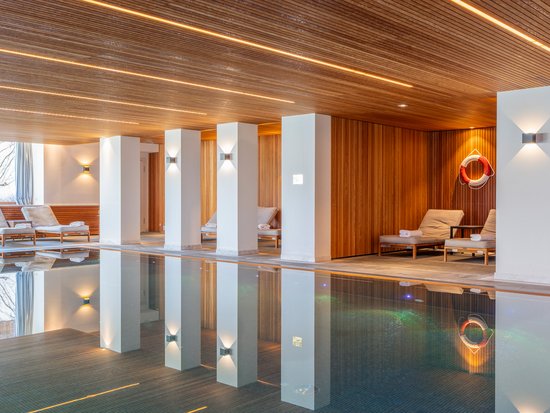Your spa hotel in Allgäu: Allgäu Sonne Indoor pool area with lounge chairs and wooden ceiling panels