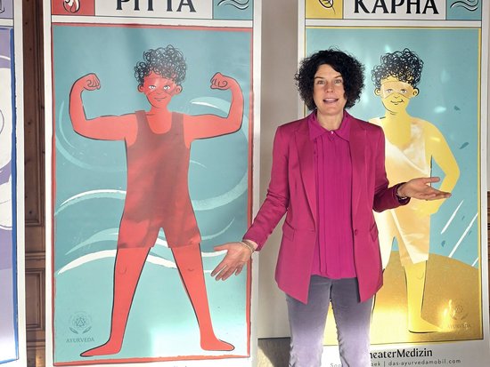 Woman standing between Ayurveda Pitta and Kapha posters