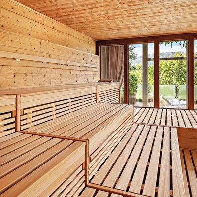 Bright wooden sauna with large windows and green outdoor view