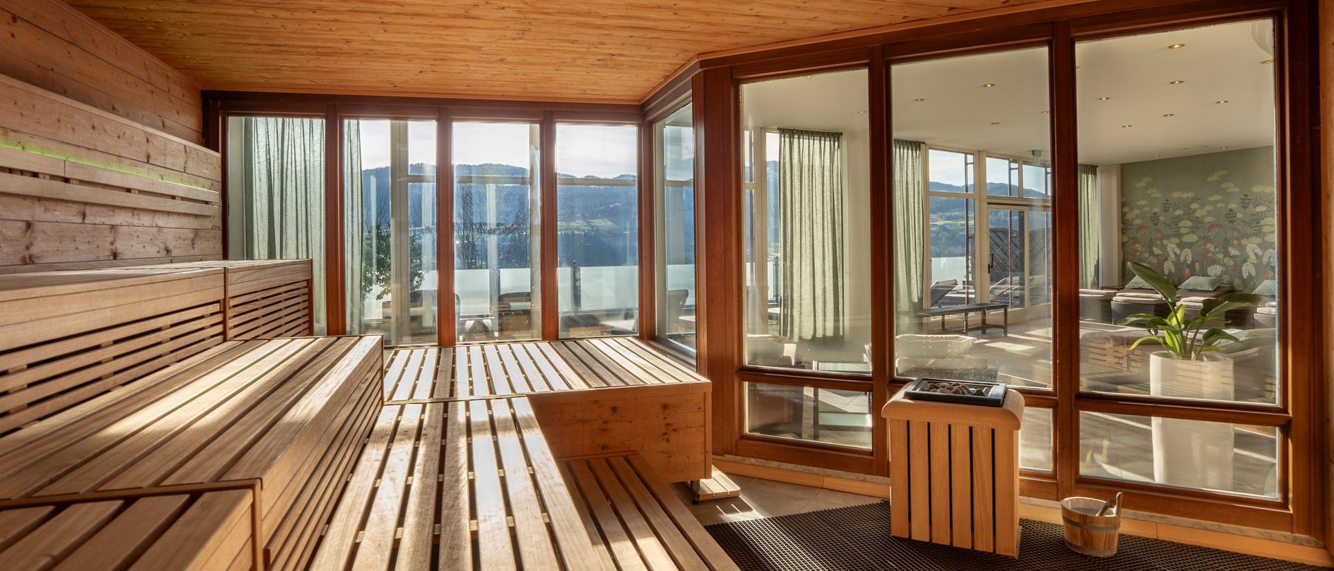 Your spa hotel in Allgäu: Allgäu Sonne Modern sauna room with wooden panels and panoramic windows showing a view
