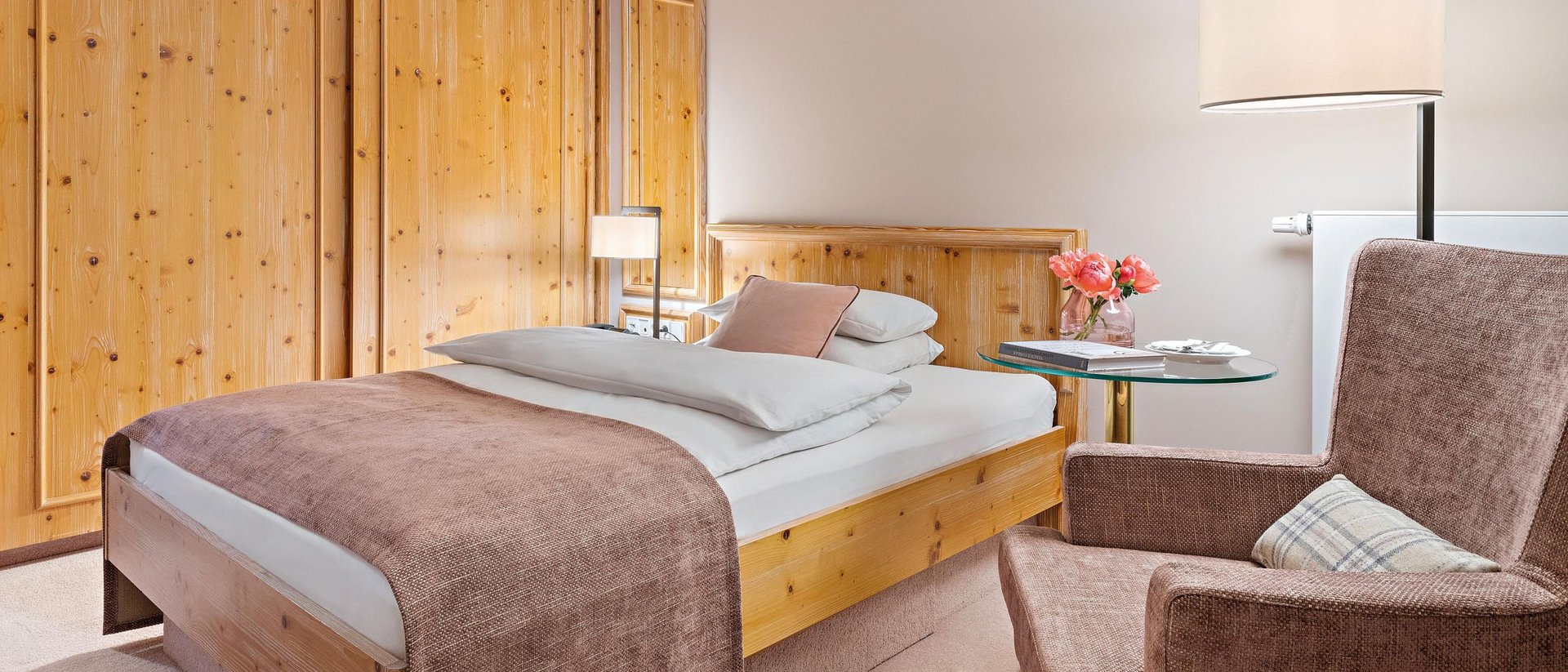 Gemütliches Schlafzimmer mit Holzmöbeln, Einzelbett und einem Sessel