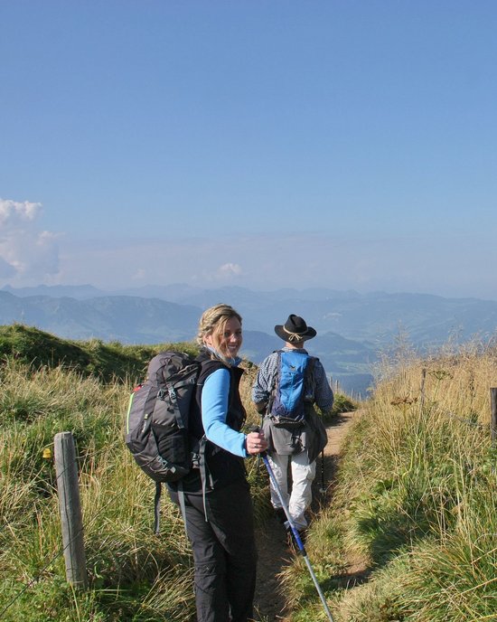 Wanderer mit Rucksäcken gehen auf einem Bergpfad bei klarem Himmel
