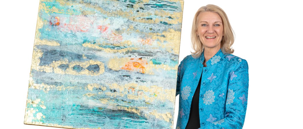 Wissen mit Weitblick – Vortragsreihe im Allgäu | Hotel Allgäu Sonne Frau hält abstraktes Gemälde mit blauen und goldenen Farben