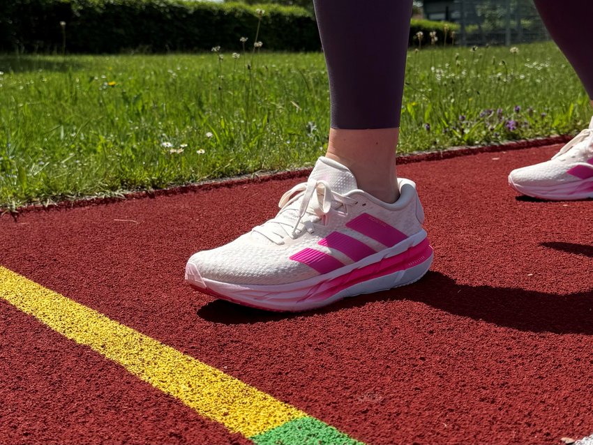 Running Camp im Allgäu Beine mit weißen Sportschuhen auf roter Laufbahn neben gelb-grüner Linie