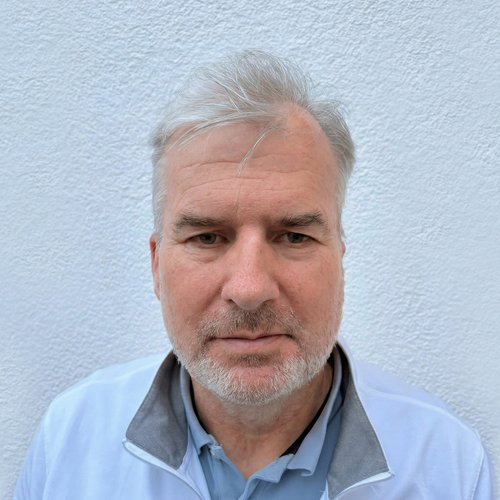 Porträt eines älteren Mannes mit grauen Haaren vor weißer Wand