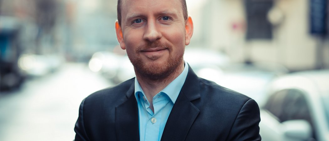 Porträt eines lächelnden Mannes in Anzug auf belebter Straße