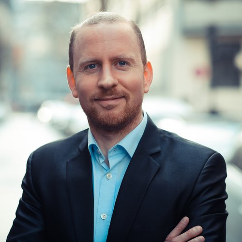 Porträt eines lächelnden Mannes in Anzug auf belebter Straße