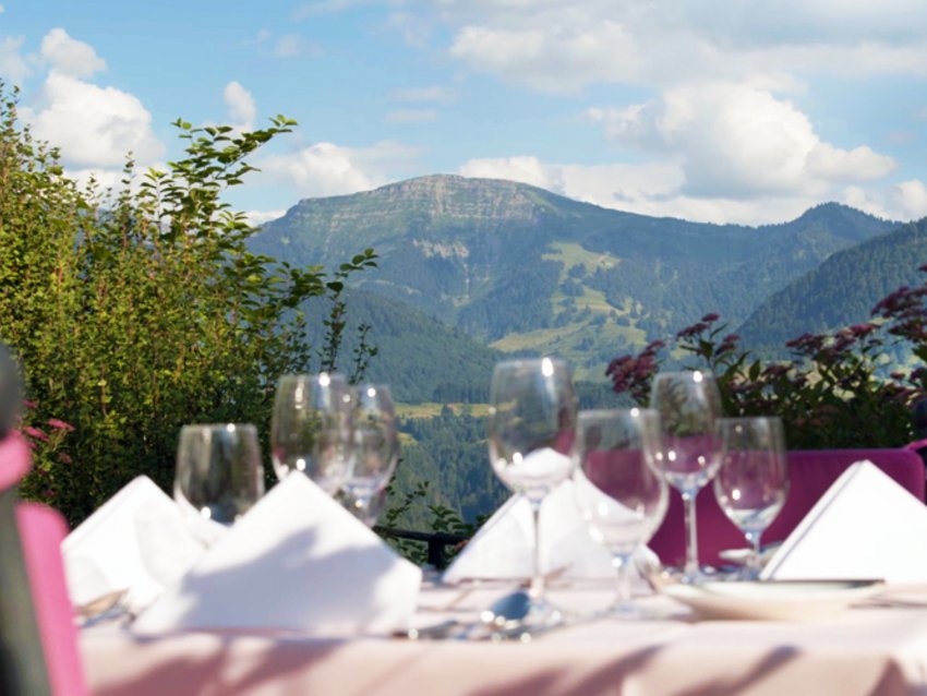 gedeckter Esstisch mit Gläsern vor Berglandschaft bei klarem Himmel
