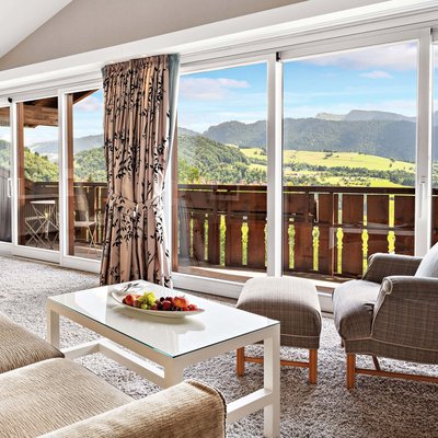 Wissen mit Weitblick – Vortragsreihe im Allgäu | Hotel Allgäu Sonne Wohnzimmer mit Sofa, Sessel und großem Fenster mit Bergblick